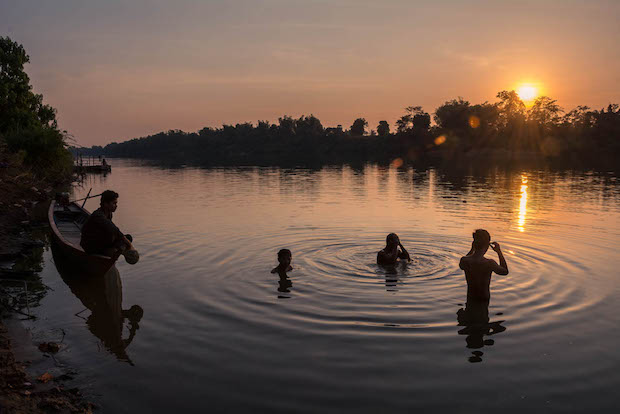 Domrae Village, Koh Tnaot Island, Kratie Province, Cambodia. Men bathing in a channel between two islands in the Mekong River at sunset. The village will be submerged by floodwaters if the Sambor hydropower dam goes ahead as scheduled. Photo credit: RodHarbinson.com